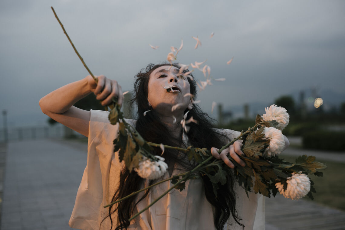 a person holding several flowers and blowing some petals from their mouth