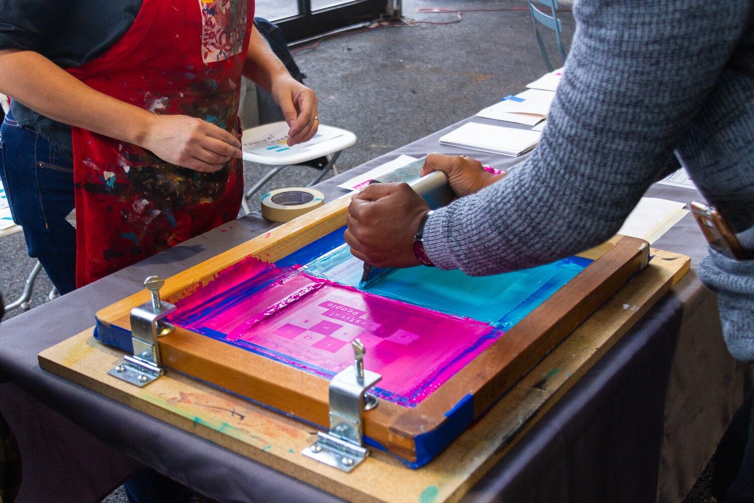 two people screenprinting, only their hands and the screen showing