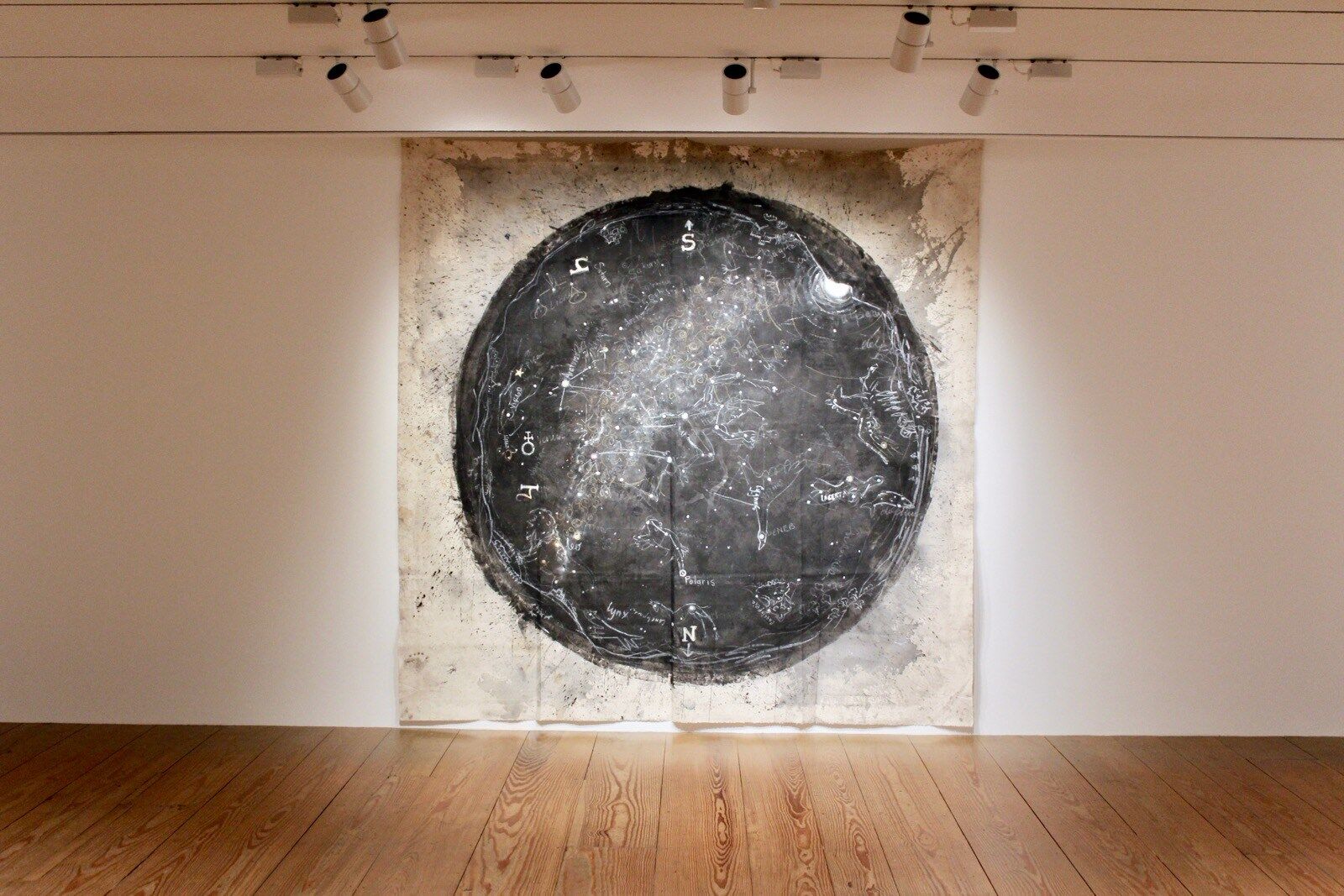 Image of white tapestry with black circle hanging on a wall