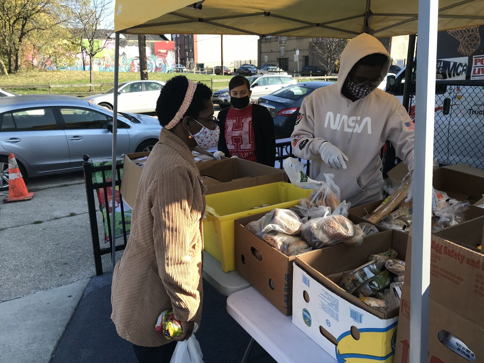 a person picking out food from a selection of groceries beneath a tent outdoors