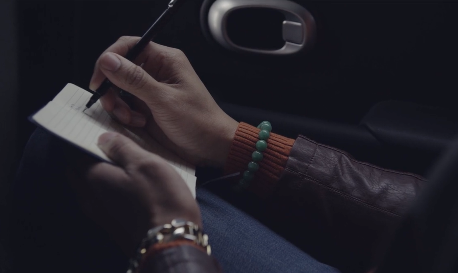 Hands writing in a notebook in a car