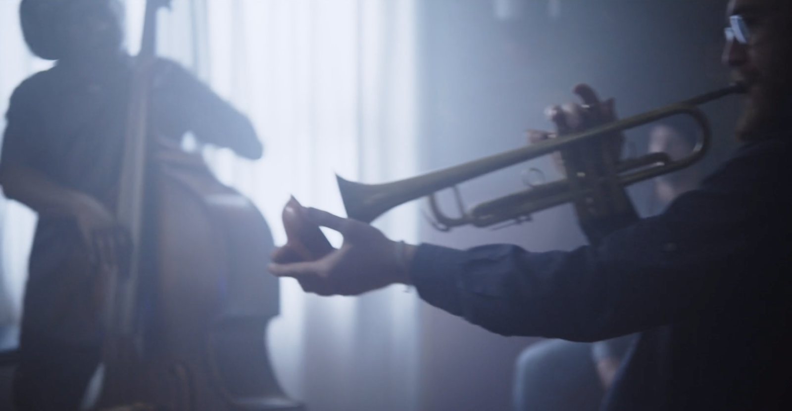 Silhouetted people playing a standup bass and trumpet