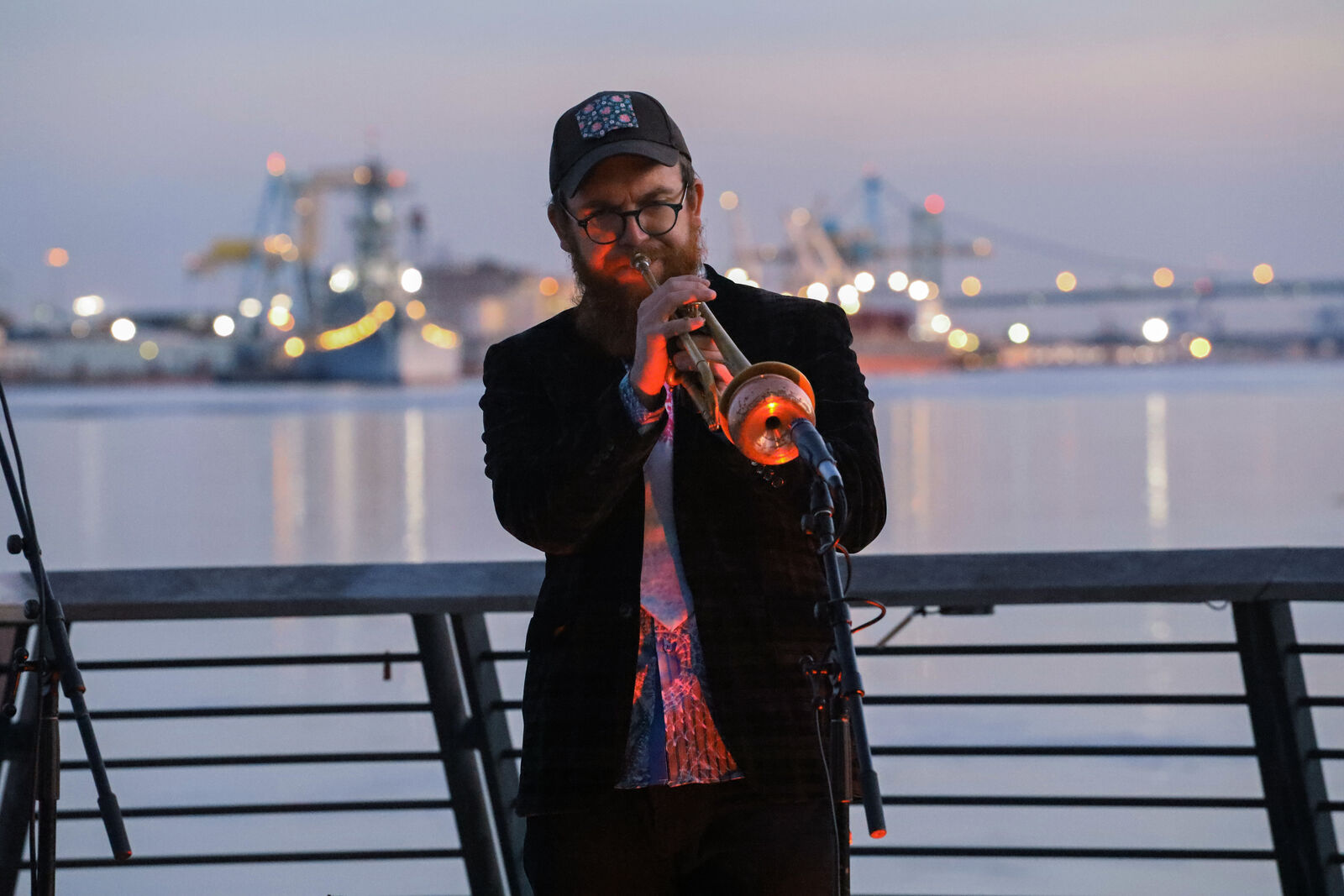 man plays trumpet in front of the waterfront