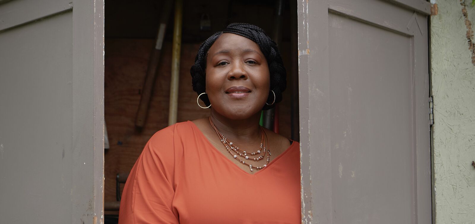 woman smiling stands between two doors