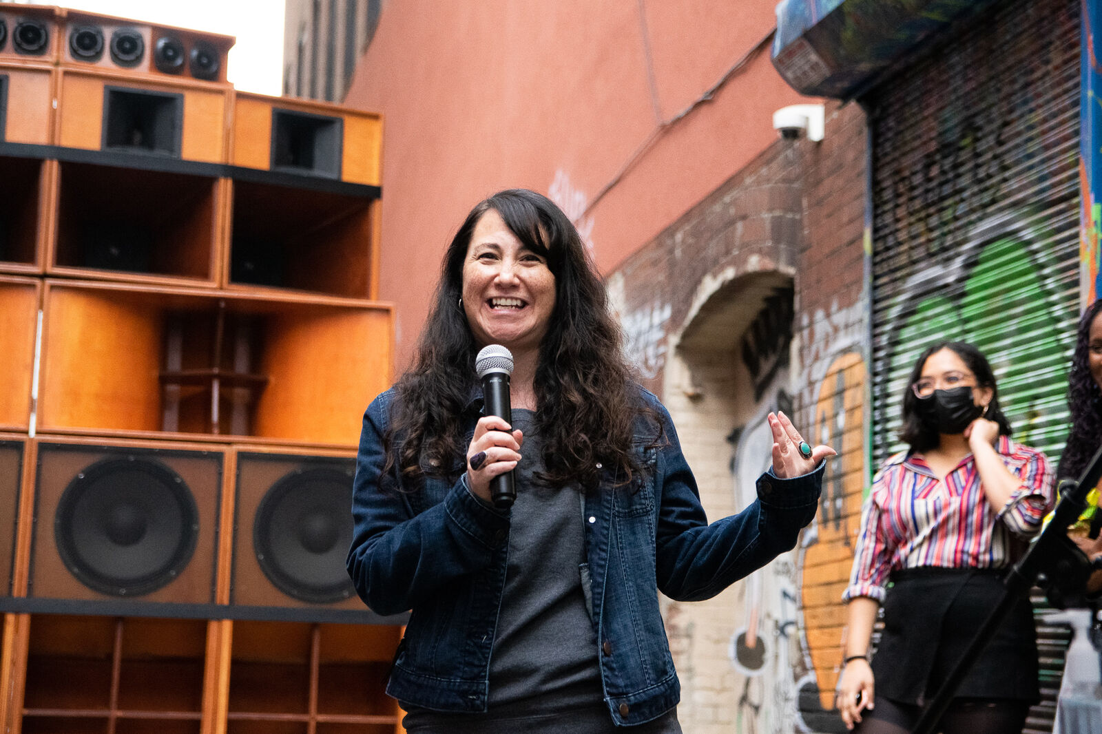 woman smiling speaking poetry on a microphone