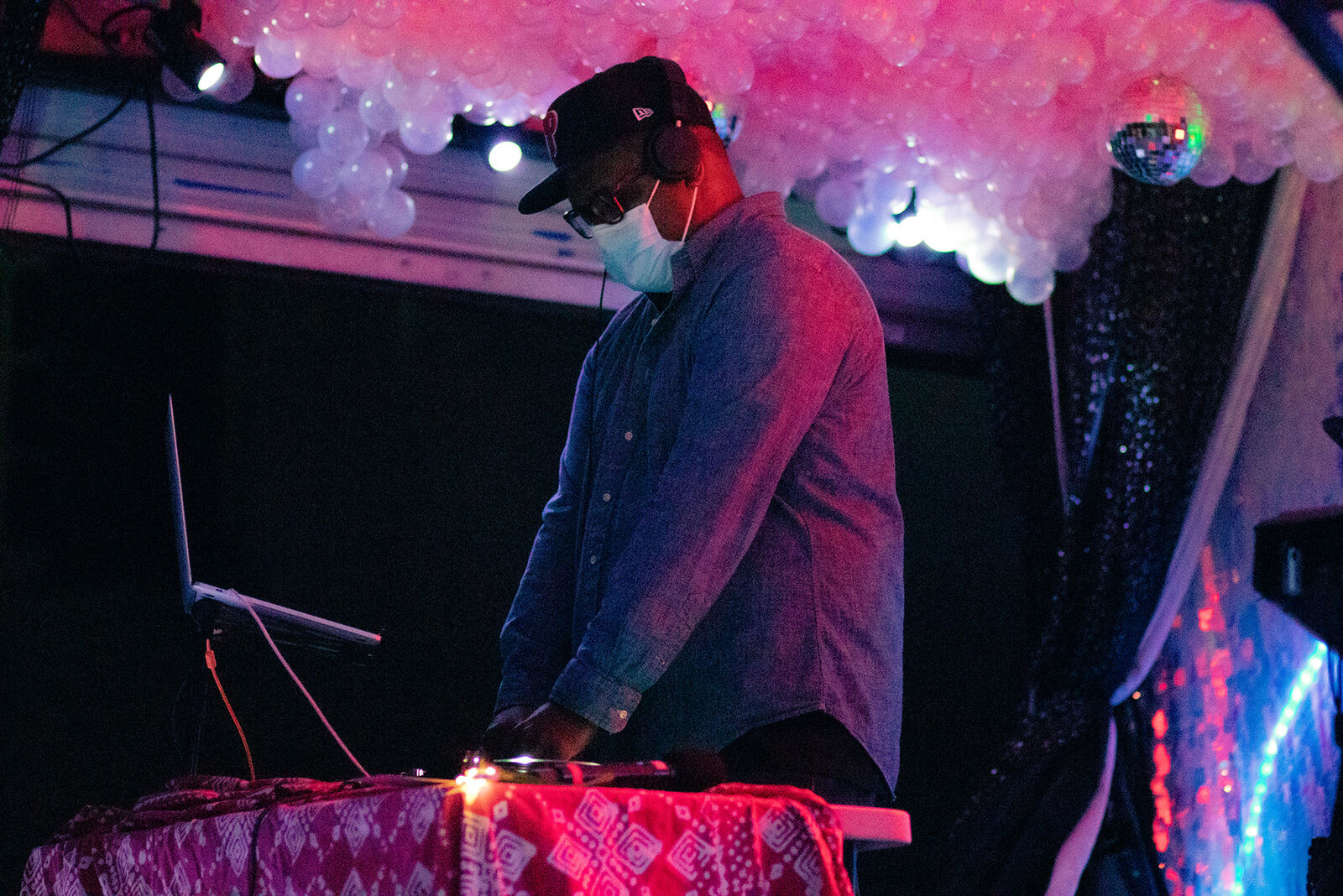 a man DJs on a stage lit by pink lights