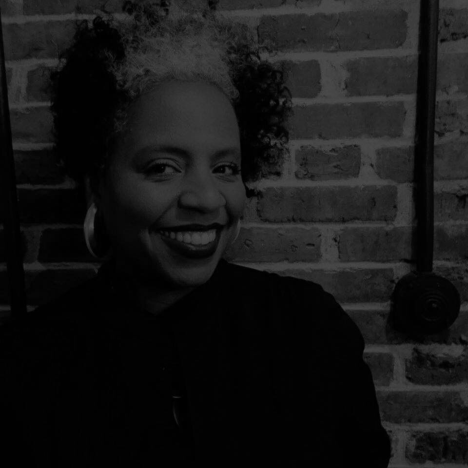 woman smiling in front of brick wall