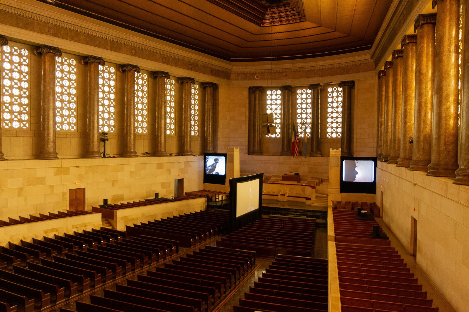 interior of a church dimly lit with multiple project screens with films playing inside the space