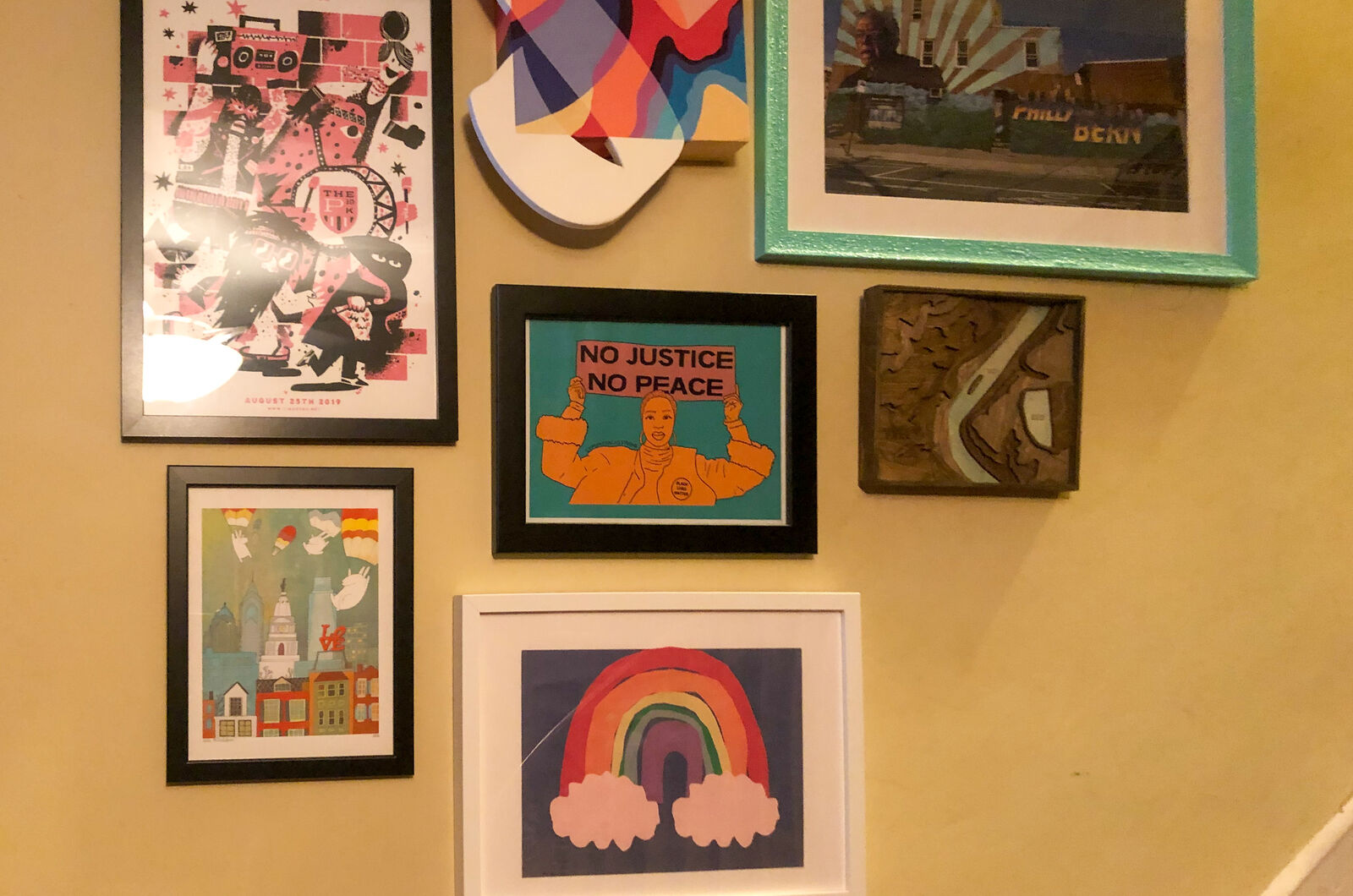 rainbow made of cut paper hangs on the wall with other framed art