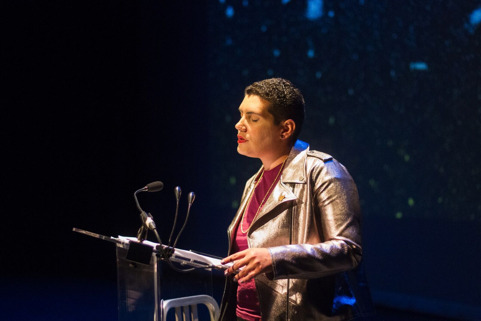 person stands at a podium reading poetry