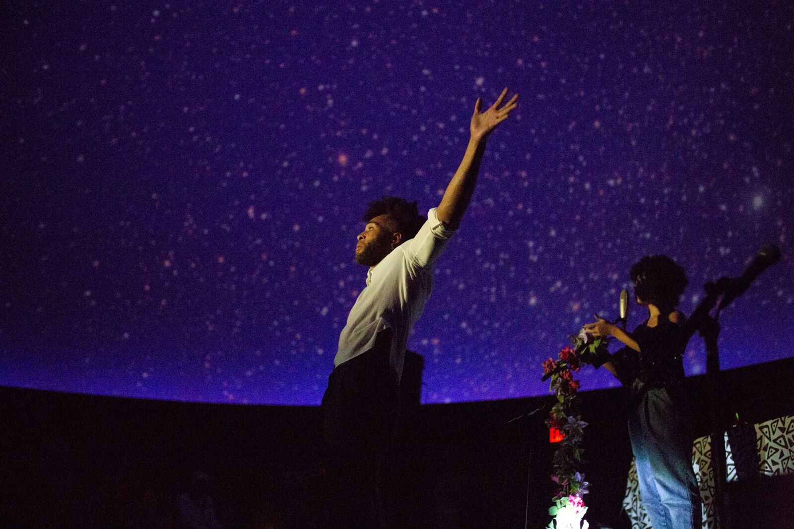 man with hands up with projections of start behind him