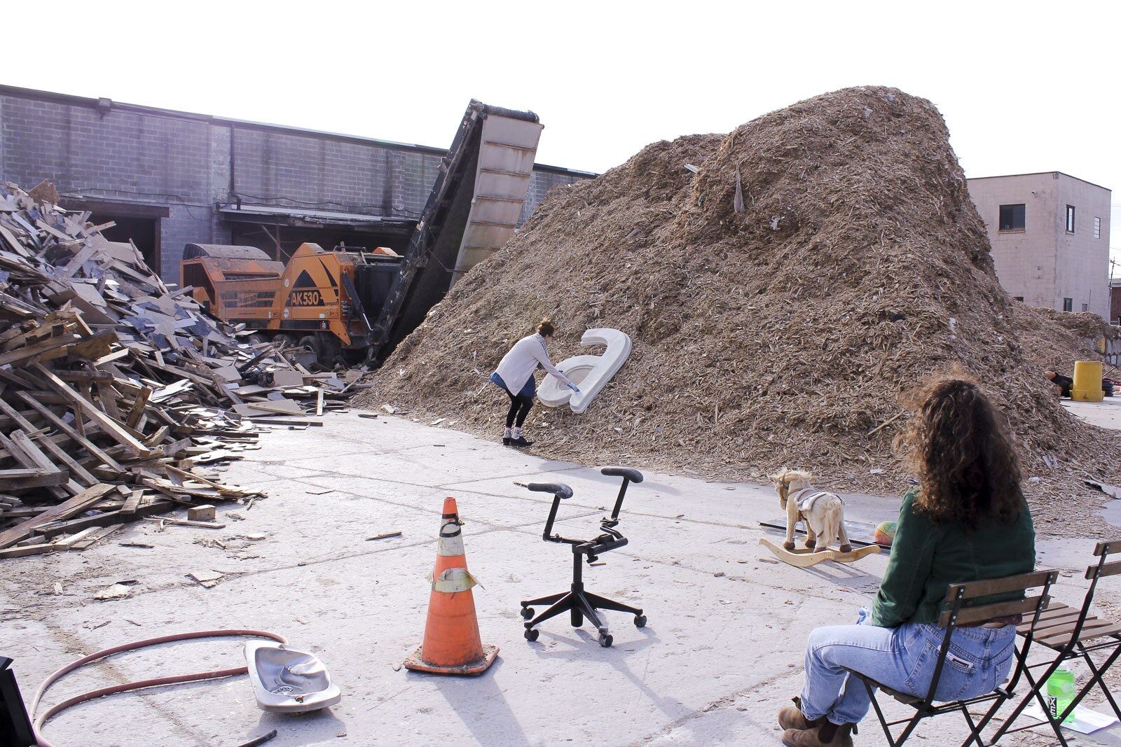 large letter "a" placed on a mound of dirt, people look on