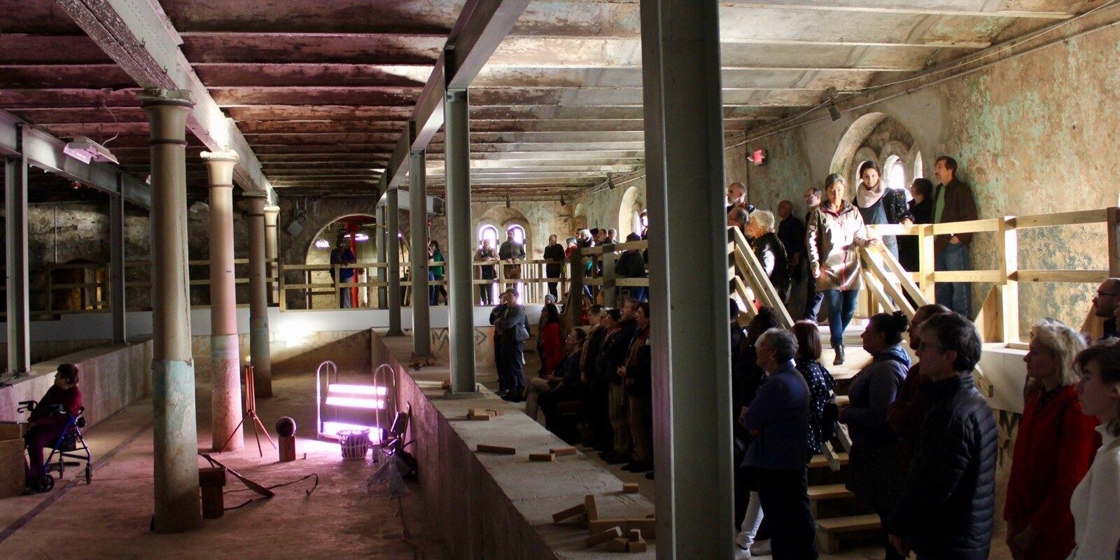 people file into dark space with columns and projections