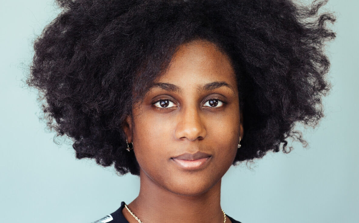 woman with natural hair smiles slightly in a portrait