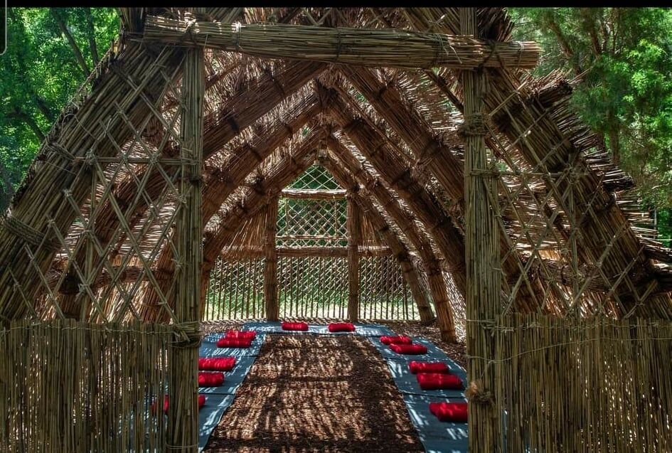 woven hut made of reeds with red seat cushions on the flour