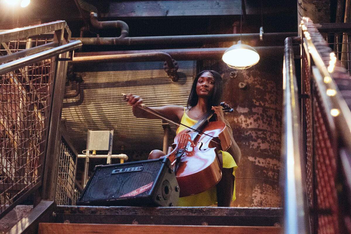 Young woman playing cello atop stairs