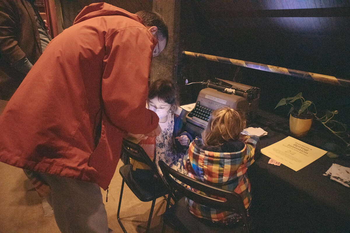 Father and two small girls in front of typewriter